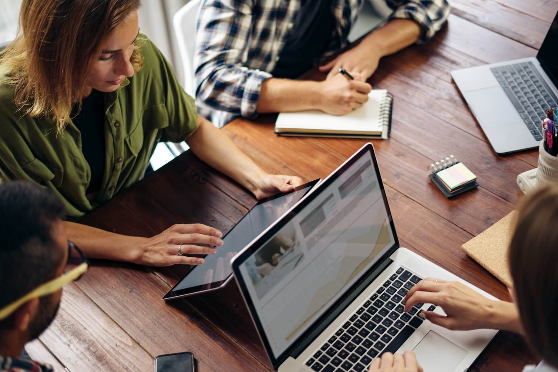xRM: Team arbeitet gemeinsam an Laptop und Tablet an digitalen Projekten