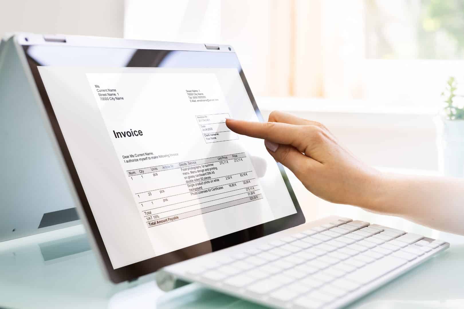 Hand zeigt auf eine E-Rechnung auf einem Laptopbildschirm