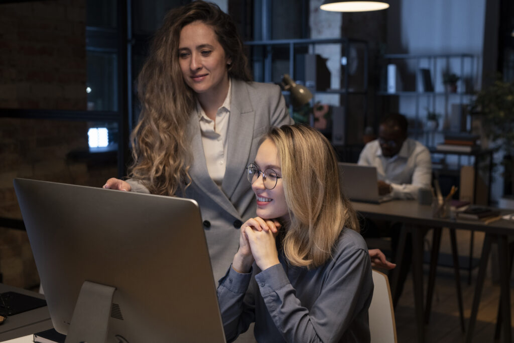 Zwei Frauen arbeiten gemeinsam an einem Desktop-Computer im Büro