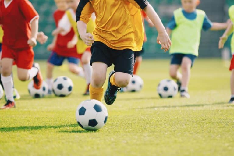 Kinder spielen Fußball auf einem Rasenplatz