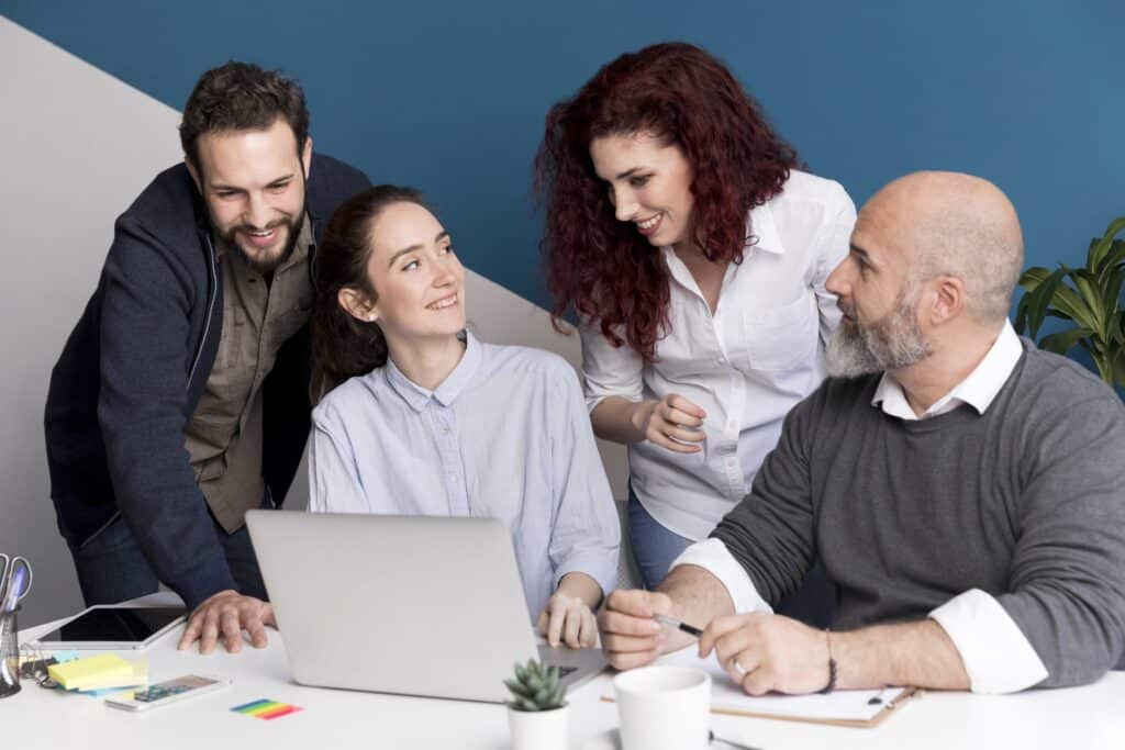 Teammeeting: Vier Mitarbeitende diskutieren gemeinsam vor einem Laptop