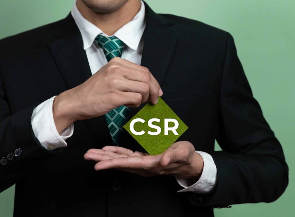 Person im Anzug hält grünes CSR-Symbol