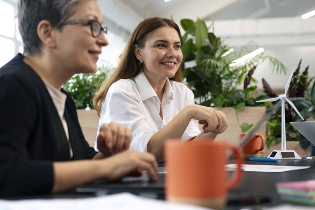 Zwei Personen arbeiten und sprechen an einem Tisch mit Laptops