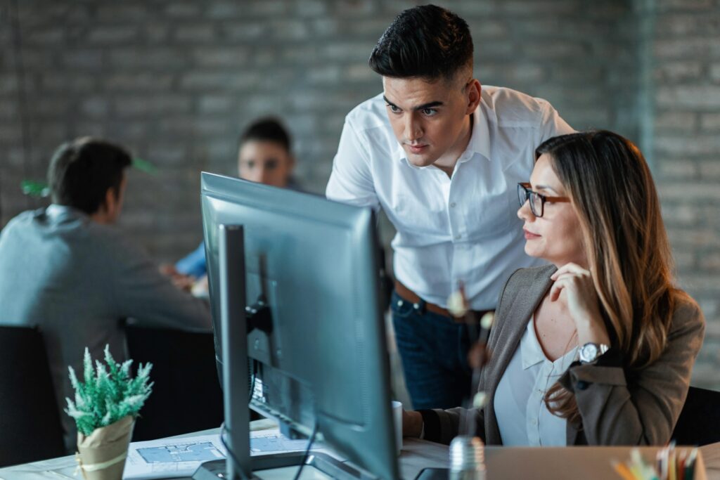Zwei Mitarbeitende schauen gemeinsam auf einen großen Monitor im Büro