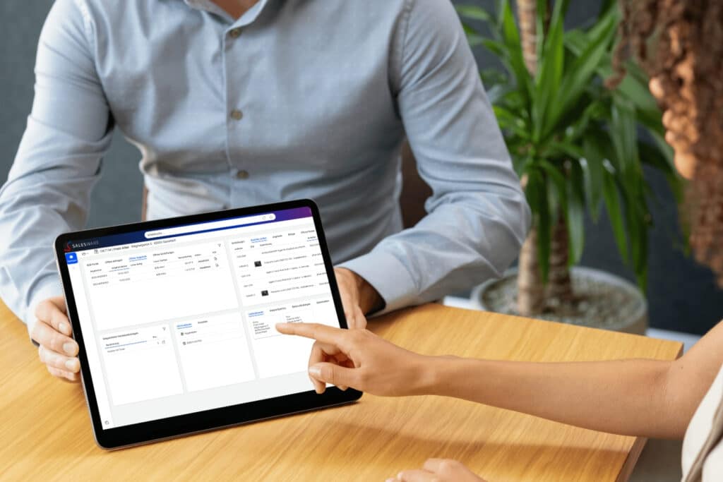 Zwei Personen analysieren Geschäftsdaten auf einem Tablet mit der Salesware-Software