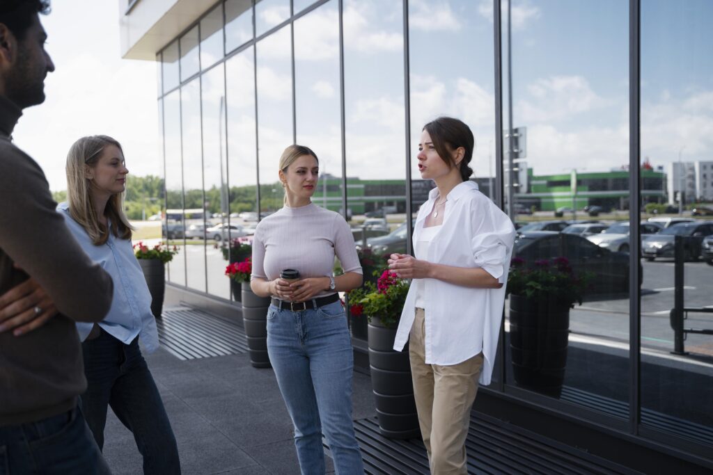 Mitarbeitende im Gespräch vor einer modernen Glasfassade im Außenbereich eines Unternehmens